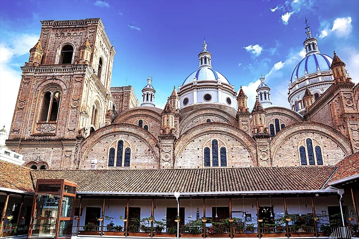 Las cúpulas de la Catedral de Cuenca asomando tras la galería colonial de teja de una plaza del centro histórico.